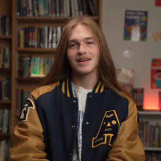 Zechariah Stone-Moore sitting in front of a library of books.